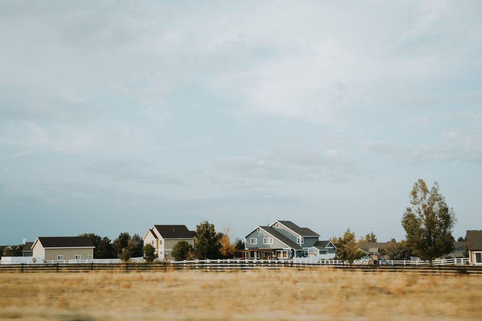 Houses near the Brown Grass Field with Fence